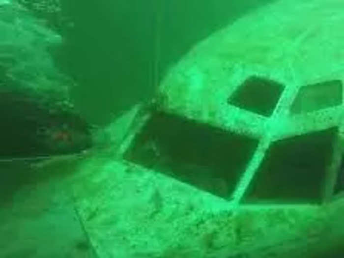 The 22-ton plane is submerged in the hazel-green waters using a barge, two cranes, two low-boys, and two police escorts. The nose sits 50-feet deep while the tail sits at just 15.