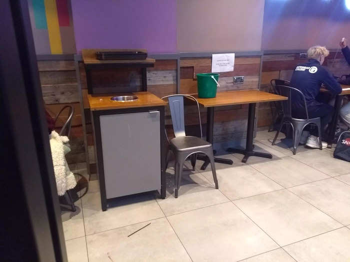 These was a small waiting area for delivery drivers with a chair, table, and bucket.