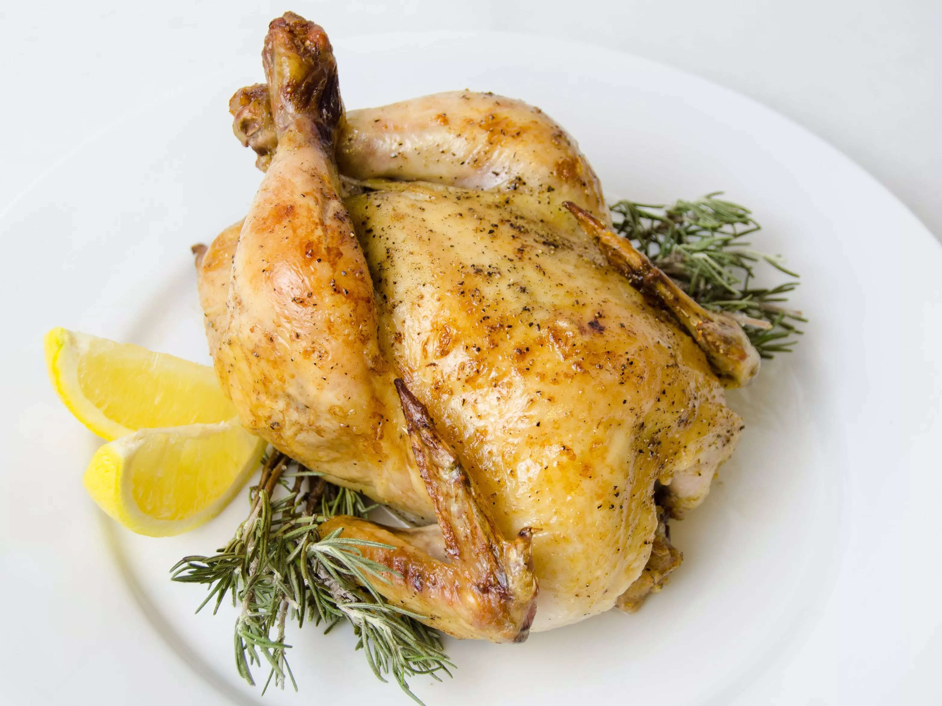 Cornish game hen plated with rosemary and lemon on a white plate