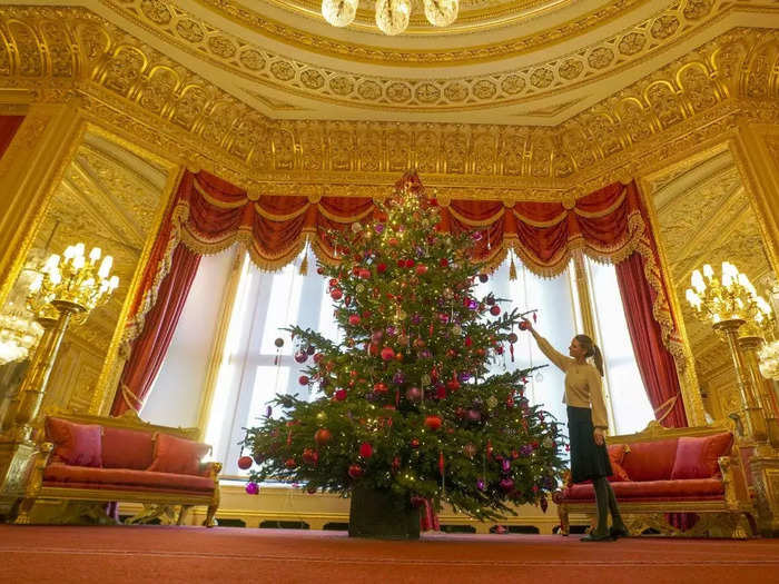 In the Crimson Drawing Room, a 15-foot Christmas tree glimmers with red ornaments to match the red curtains, carpet, and furniture.