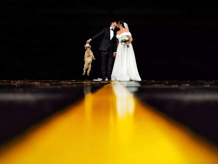 A groom proves he can multitask by giving his bride a kiss and their puppy a treat at their wedding in Vilnius, Lithuania.