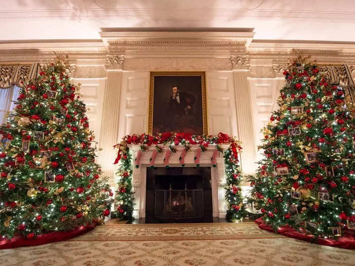 On the other side of the State Dining Room, stockings hang from the mantle in between two large Christmas trees.