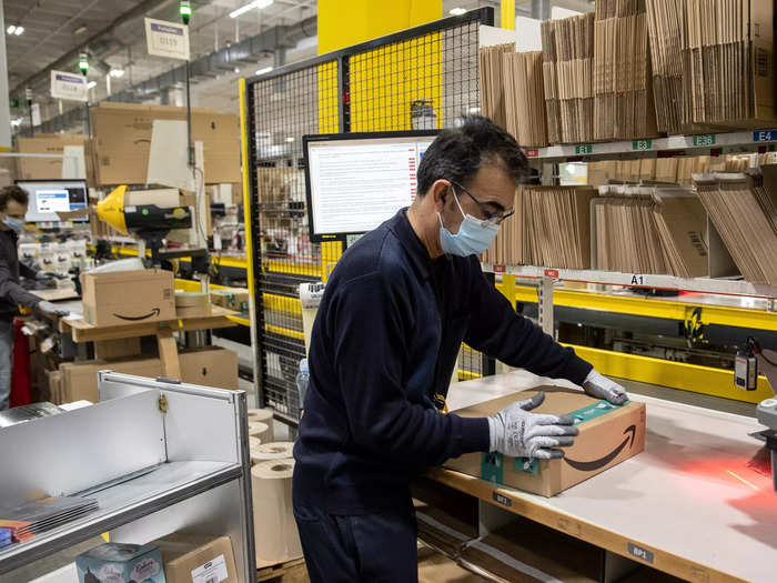 The coat travels through the warehouse on the conveyor belt and arrives at a packing station. Here, a computer instructs the packer on what size box to use. Then, the packer tapes it up and labels the package with an order barcode.