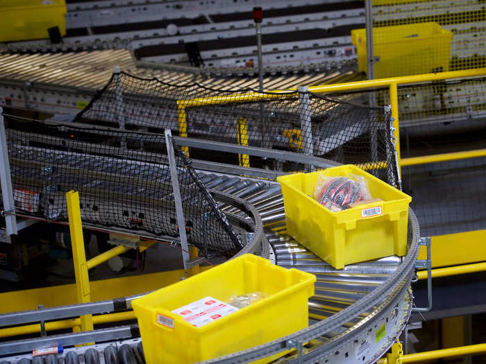 A picker takes the coat off of the pod and puts it into a yellow crate which is then placed on a conveyer belt.