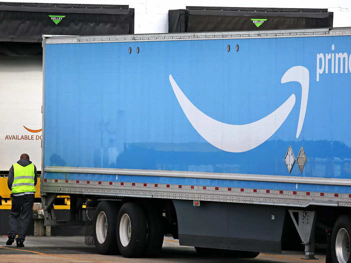 The trucks arrive at the inbound loading dock of an Amazon Fulfillment Center where dock workers unload the packages. Associates then transfer the packages onto pallets.