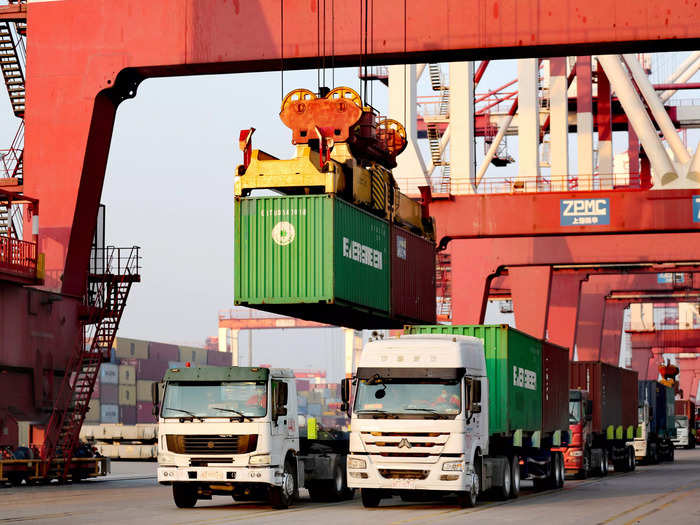 The shipping container is dropped off at the port and eventually loaded onto a cargo ship by longshoremen.