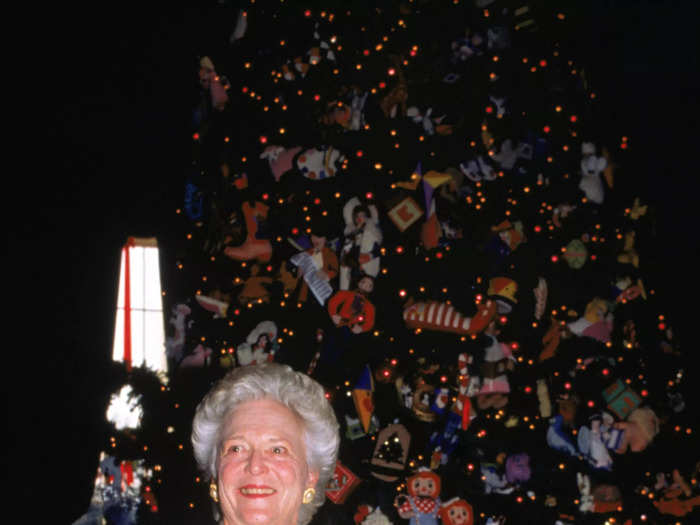 Barbara Pierce Bush posed with the official White House Christmas Tree in 1991 wearing a white striped jacket and a red skirt.