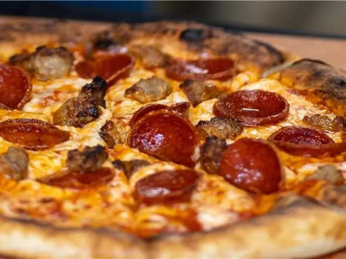 Once the dough is ready, the machine tops the pizza with sauce and other ingredients.