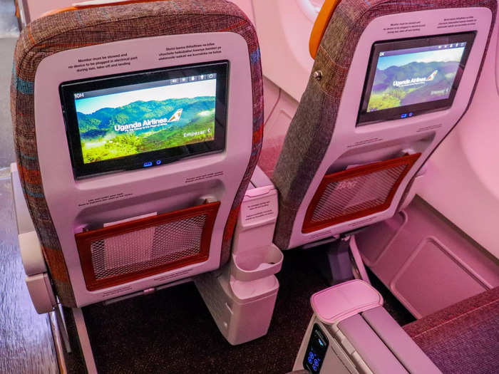 Each seat features a seat-back entertainment screen as well as USB charging ports, water bottle holders, footrests, coat hooks, and a tethered entertainment remote.