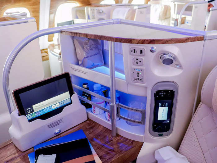 Standard seat amenities in business class include a 110v AC power outlet, USB charging port, adjustable headrest, personal reading lamp, personal mini bar, and an entertainment tablet in addition to a 23-inch in-flight entertainment screen.