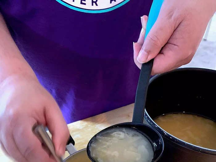 Scoop some of the hot broth with a ladle and slowly pour it into the avgolemono while continuously mixing them together with a whisk or fork.