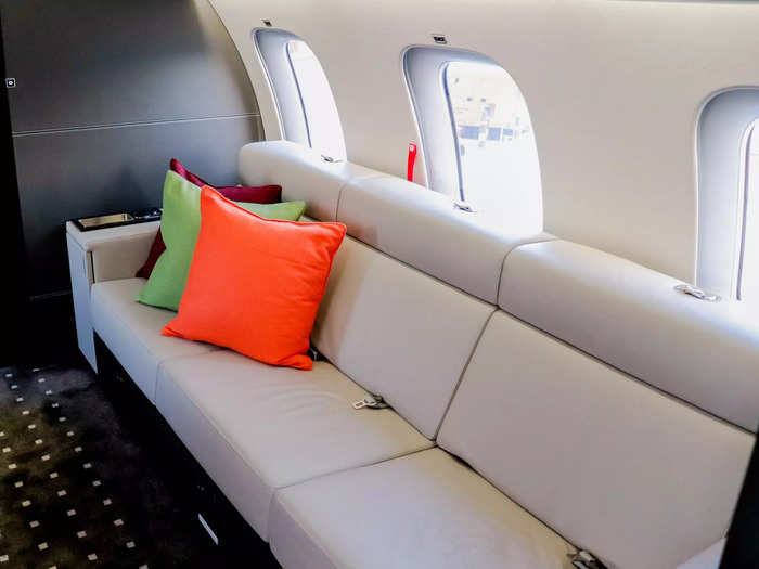 A three-place divan sits opposite a massive entertainment screen capable of playing movies or displaying a moving map with the aircraft