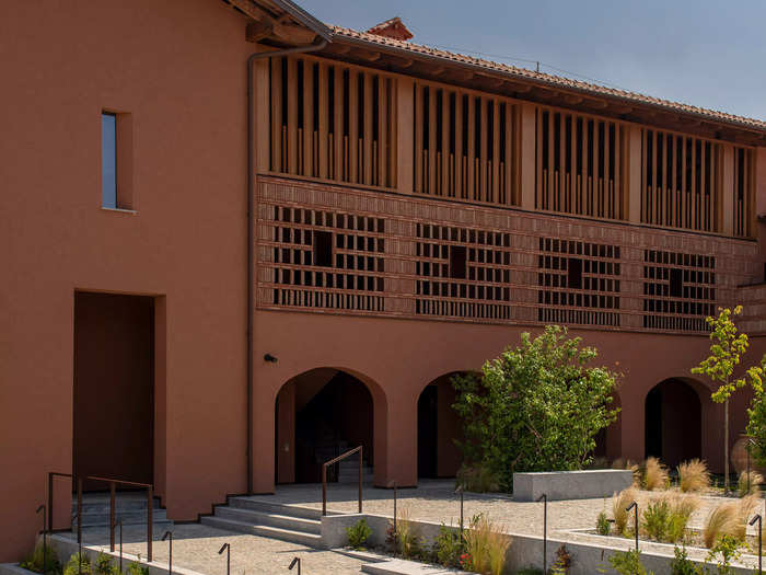 The hotel rooms are tucked behind a covered outdoor corridor