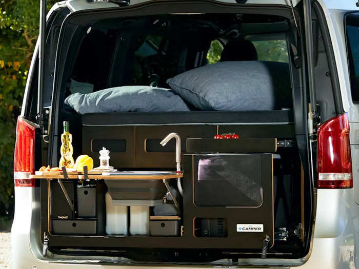 The kitchen — which extends out the rear of the van — has a sink, a two-burner gas stove, a refrigerator, and drawers for utensil and cutlery storage.