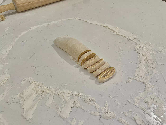 Roll the flattened dough over itself several times and cut into small strips.