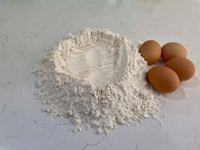 First, use the flour to create a mound with a well in the middle.