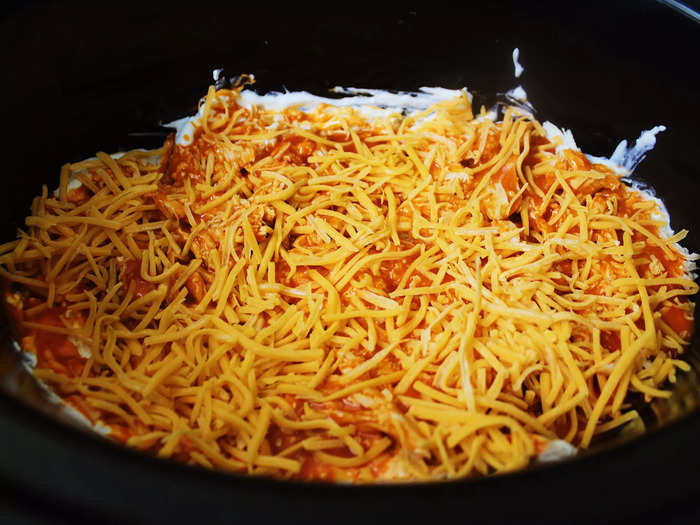 Next, I poured Buffalo wing sauce over the chicken-and-dip mixture and added a layer of shredded American cheese.