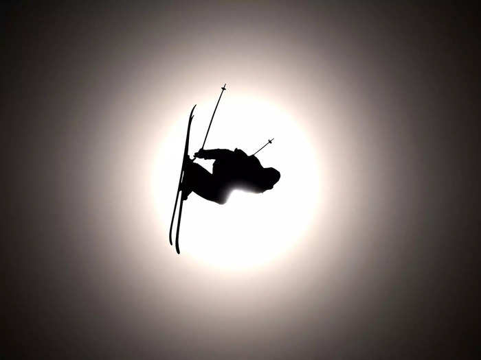 A freestyle skier takes flight in front of the Beijing sun.