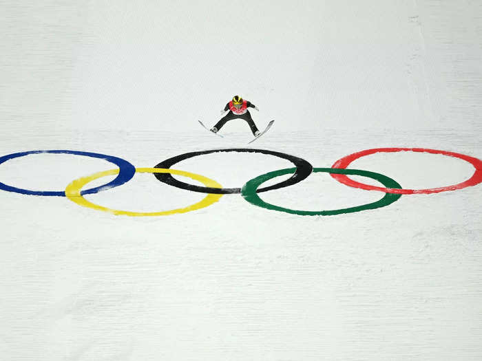 A ski jumper lands on the Olympic rings.