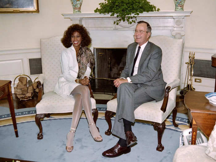 Whitney Houston looked stunning in a white dress, sparkling tights, and gold heels when she sat down with Bush one month later.