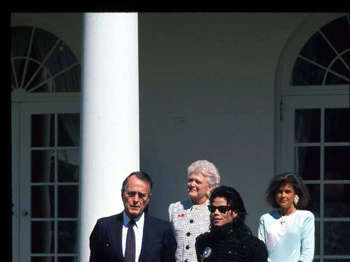 He looked stylish again for a meeting with George Bush in 1990. Jackson wore a black pantsuit with red detailing, matching sunglasses, and metallic shoes.