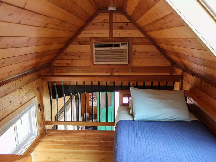 Inside the Sequoia is a warm, wood-filled tiny home. The main floor has a full-size kitchen, a propane fireplace, and a living room with a pull-out couch. Upstairs, there