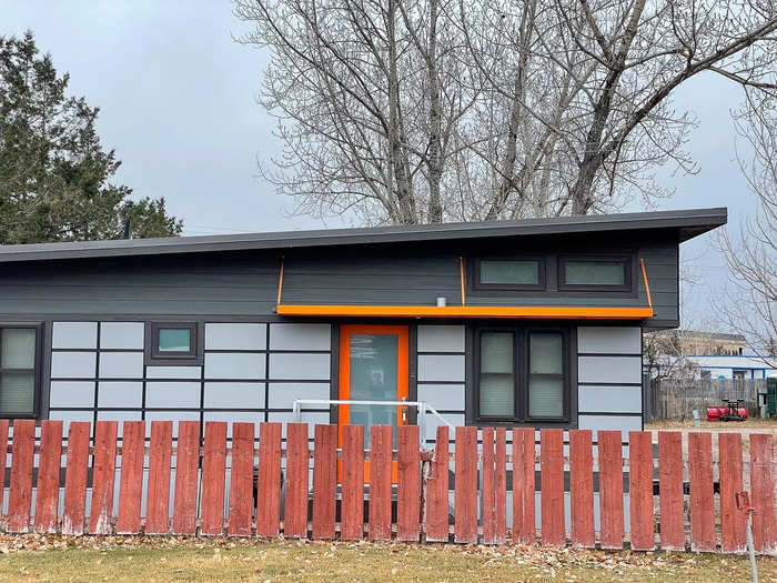 At the front of the property is a row of six tiny homes with orange, cobalt, and maroon trims.
