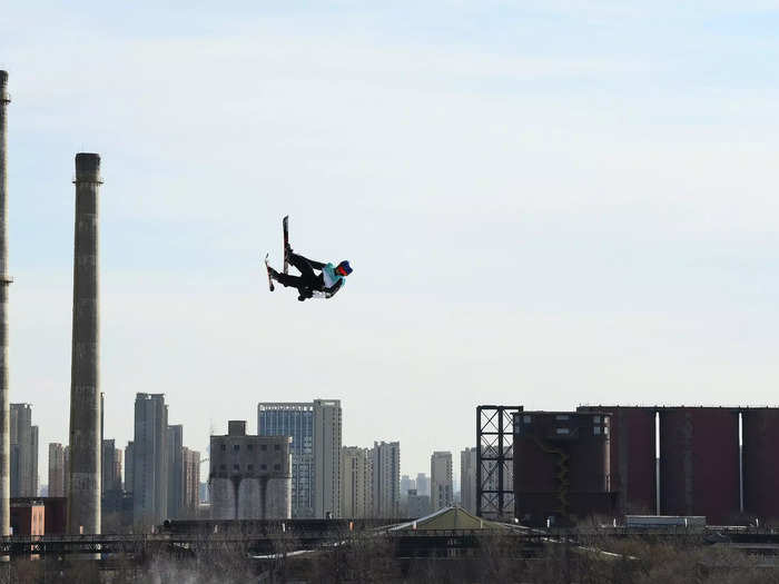 2/7: Eileen Gu flies through the air with the skyline behind her during the Big Air qualification event on Day 3 of the Olympics.