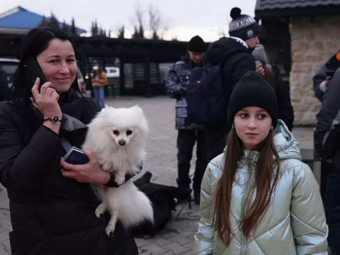 A woman held her phone in one hand and her dog in the other after crossing from Ukraine into Romania.