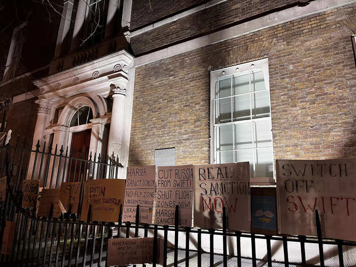 Protestors planted signs urging leaders to cut off Russia on the fence outside of a UK government building, Whitehall.