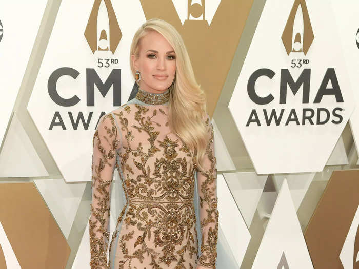 She wore this ornate beige and bronze dress with a periwinkle train on the red carpet of the 2019 CMA Awards.