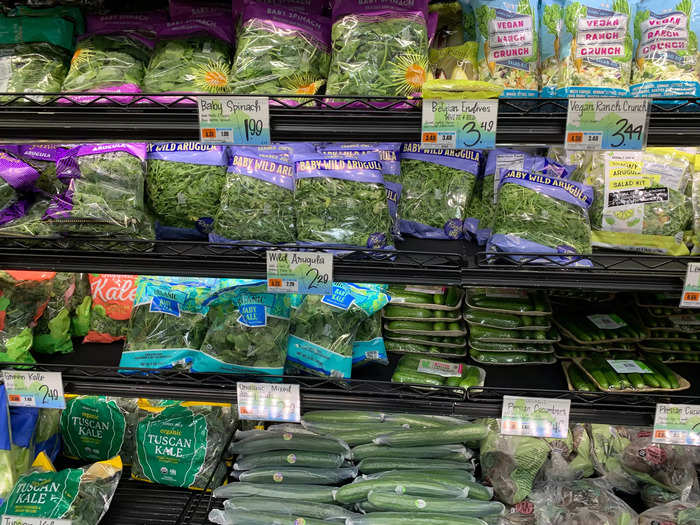 The wall behind the produce section is filled with greens and pre-packaged salads.