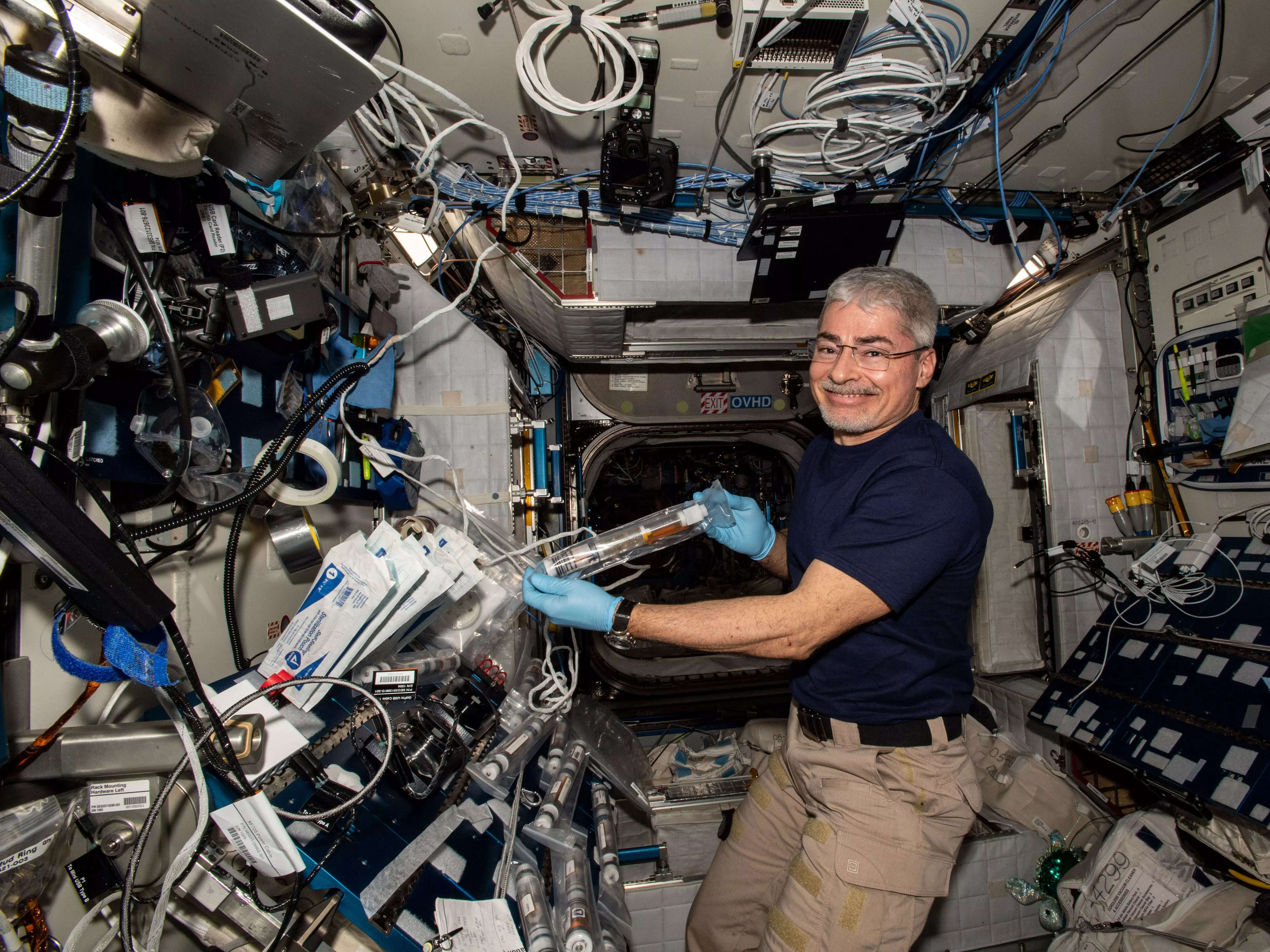 mark vande hei smiling on space station holding a tube of liquid