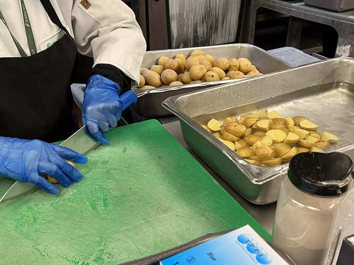 Food prep includes chopping over 500 pounds of potatoes, 400 pounds of carrots, and up to 1,000 pounds of chicken per day, among other ingredients.