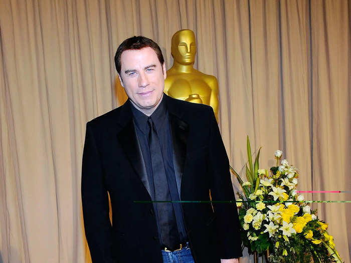 John Travolta left tuxedos behind for an underwhelming pair of jeans chosen by his wife.