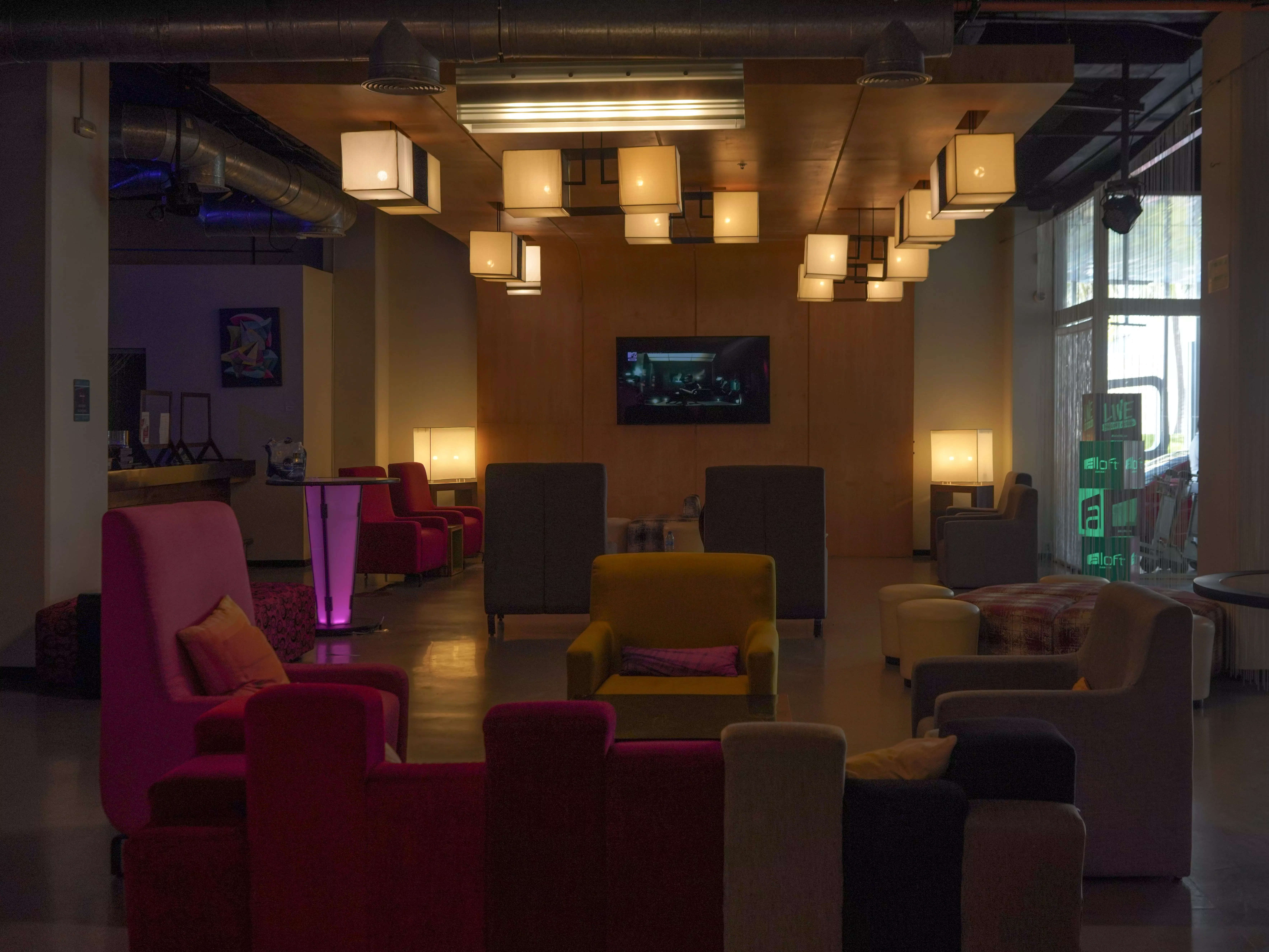 Aloft lounge with red and gray sofas, and overhead hanging lamps