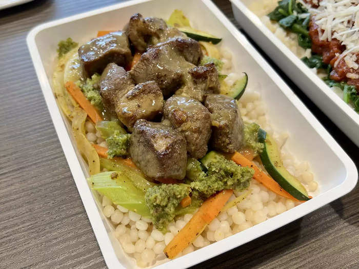 Premium economy meals include braised pork with couscous and vegetables…