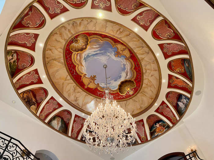 The foyer sits under 35-foot high ceilings. A French-trained Chilean artist painted a gold-leaf fresco depicting Greek gods for a ceiling centerpiece, complete with a sparkling chandelier.