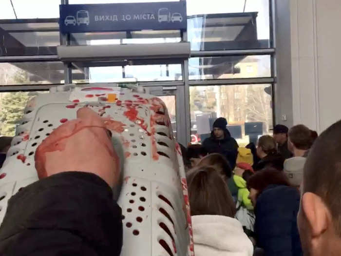 A man holds aloft a blood-stained animal carrier after the rockets struck the railway station.