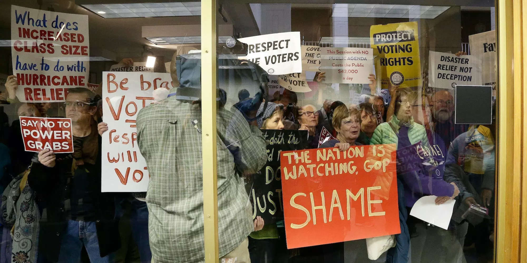 Protestors gather outside of a press conference room during a special session at the North Carolina Legislature in Raleigh, N.C., Thursday, Dec. 15, 2016.