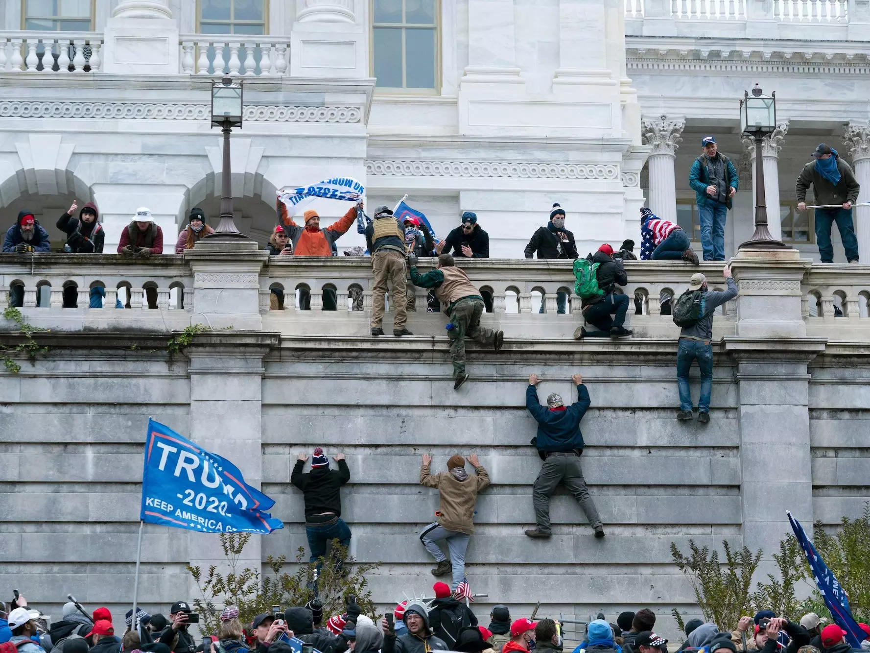 Violent insurrectionists loyal to President Donald Trump scale the west wall of the the US Capitol in Washington on January 6, 2021.