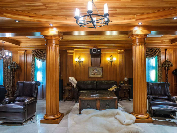 One room within the home features elegant leather furniture and wooden pillars.