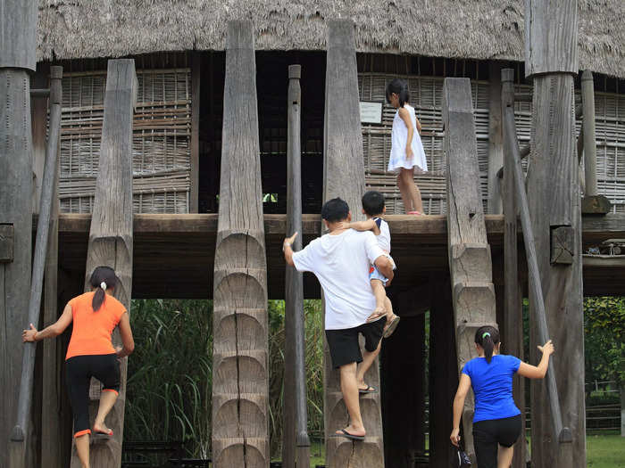 Villagers access the building by climbing up steps carved into logs.