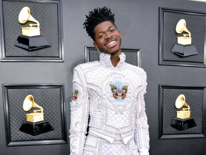 Lil Nas X showed off his flamboyant style with this quilted white ensemble covered in butterflies and pearls on the Grammys red carpet.