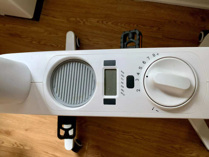 The base between the seat and the desk has a dial, a small screen, and a cupholder.