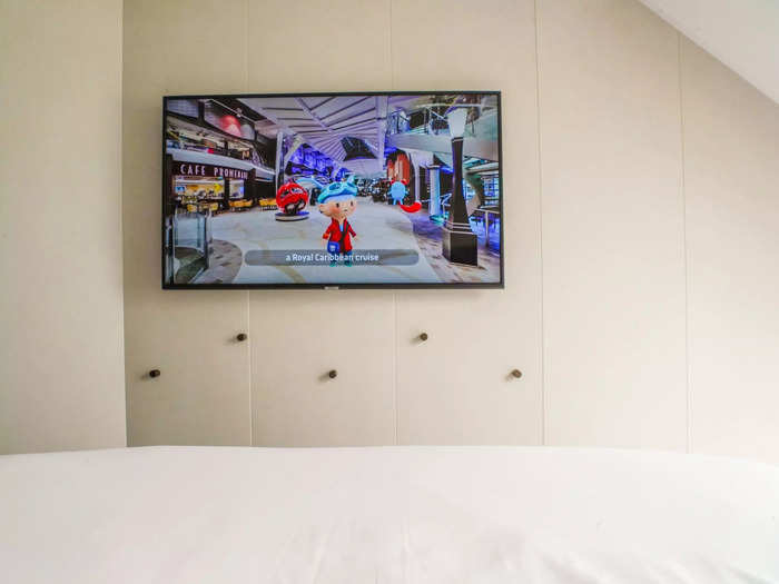 A large, flat-screen TV was mounted across from the bed with storage hooks below.