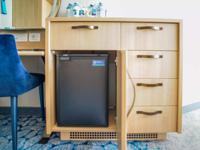 Next to the desk, a set of drawers included a cabinet with a mini-fridge inside.