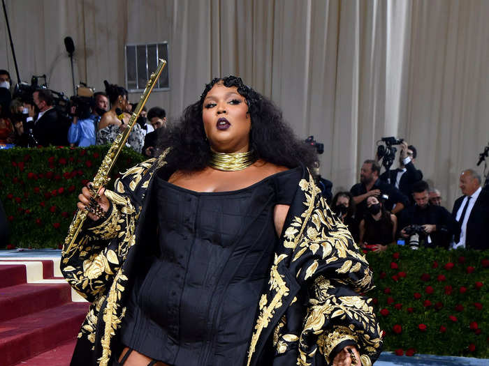 Lizzo wore a body-hugging black corset beneath a voluminous black and gold Thom Brown coat.