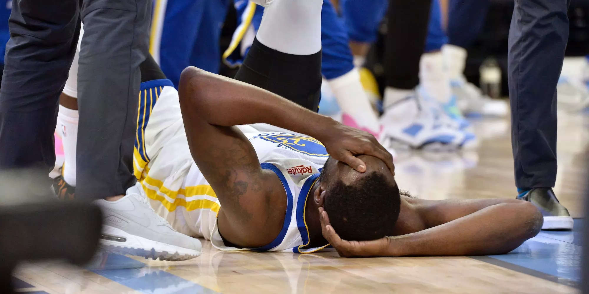 Draymond Green lays on the ground and covers his face after getting hit.