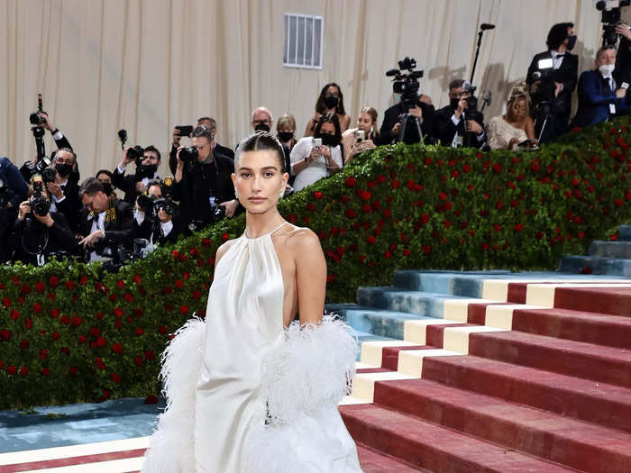 Hailey Bieber had a feather jacket draped around her sleek YSL halter gown.